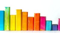 Colorful wooden blocks arranged in ascending and descending order creating bar chart pattern on white surface, representing data visualization and education concepts.