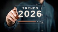 Business professional pointing at futuristic transparent screen showing trends forecast for 2026 with glowing digital interface and search bar on dark background.