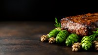 Juicy grilled beef steak with fresh green hop cones and walnuts on dark rustic background. Creative food photography for restaurant menu and culinary design.