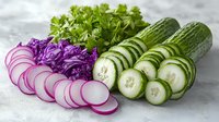 Fresh sliced vegetables arranged in rows including purple radish, green cucumber and parsley on light background, raw healthy ingredients for salad.
