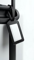 Black leather luggage tag with blank white label attached to suitcase handle for travel identification and baggage organization in monochrome style.