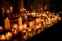 Atmospheric array of glowing candles creating warm ambience in dark interior, perfect for memorial service or spiritual ceremony.