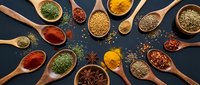 Colorful spices and herbs arranged in wooden spoons on dark background. Culinary ingredients for cooking and seasoning food preparation in kitchen.