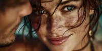 Young couple sharing intimate moment with woman's freckled face in focus, warm golden hour lighting creating romantic atmosphere for lifestyle content.