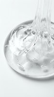 Clear gel or serum pouring into a glass bowl with bubbles and droplets, isolated on white background for skincare, cosmetics, beauty product packaging and design use.
