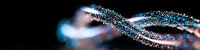 Glowing blue and white particles forming dynamic spiral waves against black background, creating futuristic abstract light trail effect for technology designs.