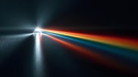 Light beam dispersing into rainbow spectrum through prism on dark surface creating colorful optical physics demonstration for science education.
