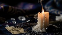 Mystical fortune telling scene with burning candle, tarot cards and lavender herbs creating atmospheric divination setup for spiritual practices.
