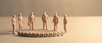 Wooden figurines standing on leadership text blocks arranged in circle on neutral beige surface, representing team management and organizational hierarchy concepts.