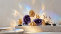 Amethyst and citrine crystals with healing stones arranged on marble surface with rainbow light reflections for meditation and spiritual wellness practices.