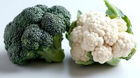 Fresh broccoli and cauliflower heads with green leaves on white background, raw organic vegetables rich in vitamins and minerals for healthy eating.