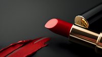 Red lipstick with smear on dark background, showcasing rich color and creamy texture for makeup artistry and beauty product photography.