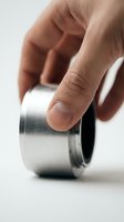 Hand holding a polished aluminum metal ring component with threaded interior, close-up studio shot on white background for industrial and engineering concepts.