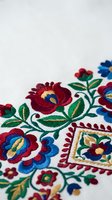 Traditional folk embroidery with colorful floral motifs on white fabric featuring red, blue and green thread work for cultural textile design projects.