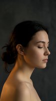 Serene young woman with closed eyes in profile view showing peaceful meditation and mindfulness practice with warm dramatic lighting on dark background.