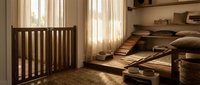 Cozy minimalist pet room with wooden crib, ramp, feeding bowls, and soft natural light, creating a warm and serene space for pets.