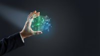 Male hand in business suit holding glowing digital circuit board with green and blue light particles, representing technology, innovation, and data processing for corporate solutions.