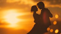 Romantic couple silhouette embracing at golden sunset with warm bokeh lights creating intimate atmosphere for wedding and love concepts.