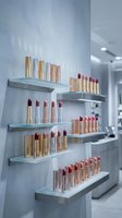 Luxury lipstick collection displayed on modern white shelves in upscale cosmetics store with gold and rose gold tubes in various red and pink shades.