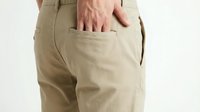 Male hand inserting wallet into back pocket of beige cotton pants, demonstrating secure storage and everyday carry solutions for personal belongings.