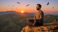 Young bearded man meditating at sunrise on mountain peak with flying birds overhead, peaceful morning meditation practice in nature for wellness and mindfulness.