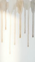 Abstract watercolor drips in neutral beige and brown tones flowing downward on white background for modern artistic design projects.