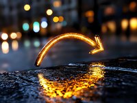 Glowing neon arrow curves downward on wet asphalt surface, reflecting golden light against dark urban background with blurred bokeh lights at night.