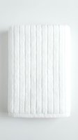 Folded white cotton bath towel with ribbed texture on a light background, perfect for spa, hotel, and bathroom decor concepts.