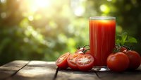Fresh tomato juice in glass with ripe red tomatoes and basil on wooden table in sunny garden setting for healthy lifestyle and nutrition concepts.