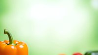 Fresh orange bell pepper on soft green blurred background with copy space for healthy cooking and nutrition concepts.
