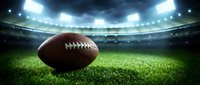 American football on green grass field in stadium with bright lights and dramatic sky for sports marketing and game day promotions.