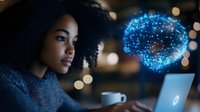 Young African American woman working on laptop with glowing digital brain hologram representing artificial intelligence and machine learning technology.
