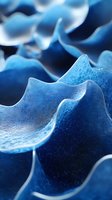 Abstract microscopic view of blue cellular membrane structure with wavy patterns and textured surface showing intricate biological detail at macro scale.