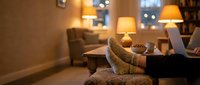 Cozy evening living room interior with warm lighting, comfortable armchair, sofa and table lamps creating relaxing home atmosphere for leisure and comfort.