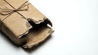 Vintage brown paper package tied with natural twine string on white background, rustic gift wrapping for holidays and special occasions.