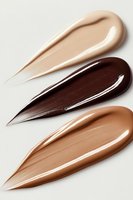 Creamy foundation smears in different skin tones from light to dark on white background, showing smooth texture and glossy finish for cosmetic advertising.
