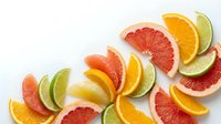 Fresh citrus fruit slices arranged on white background including orange, grapefruit, lime and lemon wedges for healthy eating and vitamin C nutrition.