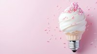 Innovative light bulb concept with soft serve ice cream top and pink sprinkles against pastel pink background, creative food photography for advertising.