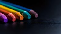 Colorful chalk pastels arranged diagonally on dark background with dramatic lighting and selective focus, creating artistic composition for creative design projects.