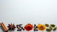 Aromatic spices and seasonings arranged on white background including cinnamon, star anise, cloves, paprika, turmeric and cardamom for culinary use.