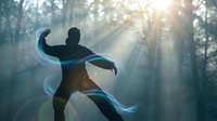 Male martial artist practicing tai chi with flowing energy ribbons in misty forest at sunrise creating peaceful meditation atmosphere.