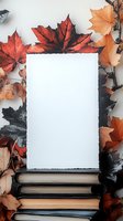 Blank white card on stack of books surrounded by vibrant autumn maple leaves in red, orange, and black tones, perfect for seasonal messaging.
