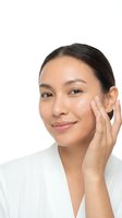 Young Asian woman applying face cream moisturizer on white background isolated for skincare beauty routine and cosmetic product advertising.