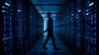 Blurred technician walking through modern data center server room with blue LED lights and network equipment racks for cloud computing and IT infrastructure.
