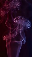 Abstract colorful smoke swirls in red purple and blue hues creating elegant flowing patterns against dark background for creative design projects.