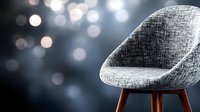 Modern gray upholstered chair with wooden legs against dark background with soft bokeh lights creating contemporary minimalist interior atmosphere.