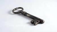 Antique iron skeleton key with ornate oval handle and aged patina, isolated on white background for design, clipart, and vintage decor projects.