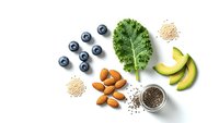 Healthy superfood ingredients including fresh blueberries, kale, avocado, almonds, quinoa and chia seeds arranged on white background for nutrition.