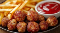 Juicy grilled meatballs served with crispy french fries and red sauce on dark plate, close up view. Restaurant appetizer or main course meal.