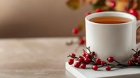Warm cup of tea with festive red berries on wooden table creating cozy holiday atmosphere for seasonal celebrations and winter comfort moments.